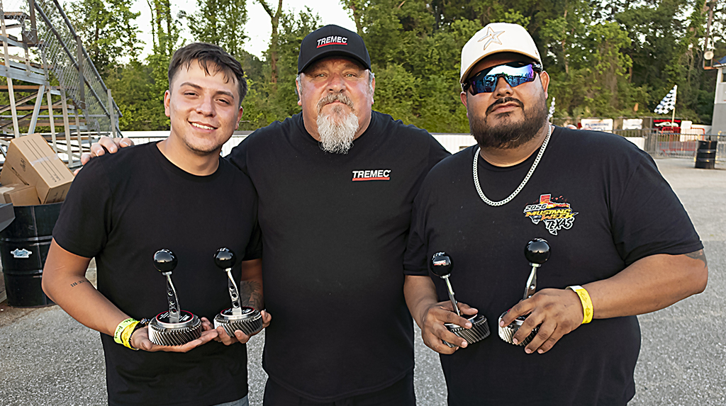 Saul Contreras and Jesse Rodriguez stand next to TREMEC's Mike Kidd with their TREMEC Stick Shift Shootout trophies at Mustang Week Texas 2026