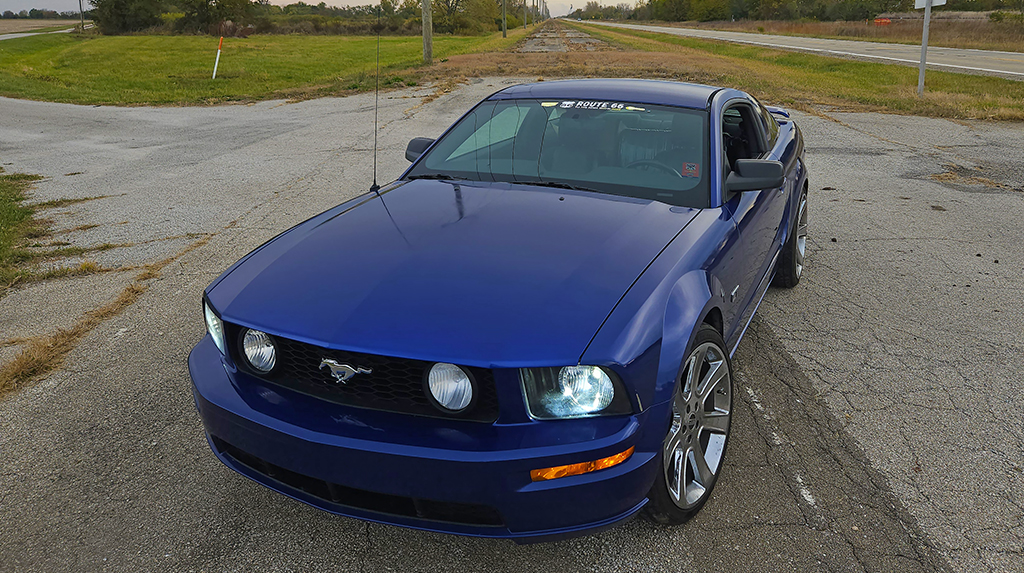 2005 Ford Mustang GT in factory blue parked on an old stretch of Route 66 in Illinois