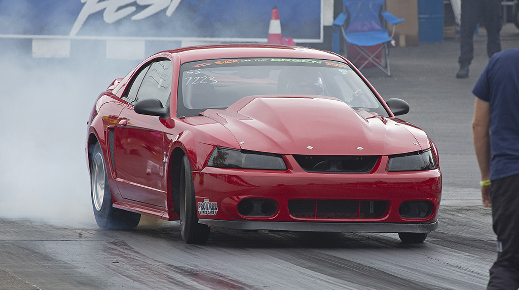 A red 1999 Ford Mustang does a burnout at the Beech Bend Raceway dragstrip during the TREMEC Stick Shift Shootout
