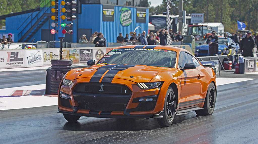 An orange Ford S550 Shelby Mustang GT500 races past the Christmas tree at South Georgia Motorsports Park during the 2026 Mod Motor Nationals