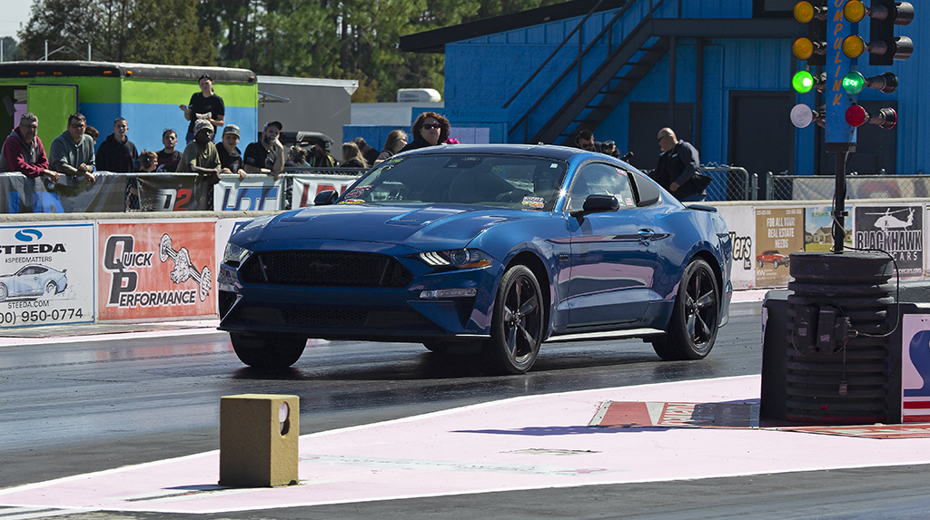 A 2022 Ford Mustang GT launches from the starting line while drag racing